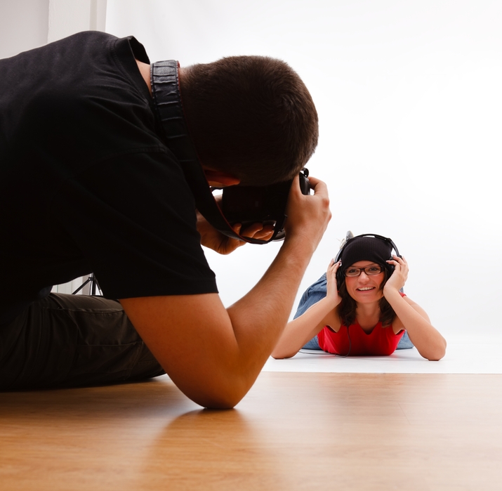 Ein Fotograf fotografiert eine Frau, die am Boden eine Position am Boden, für ein Foto einnimmt