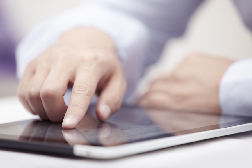 Eine Person zeigt mit seinem Finger auf ein Tablet. Er verfolgt mit seinem Finger Textinhalten.