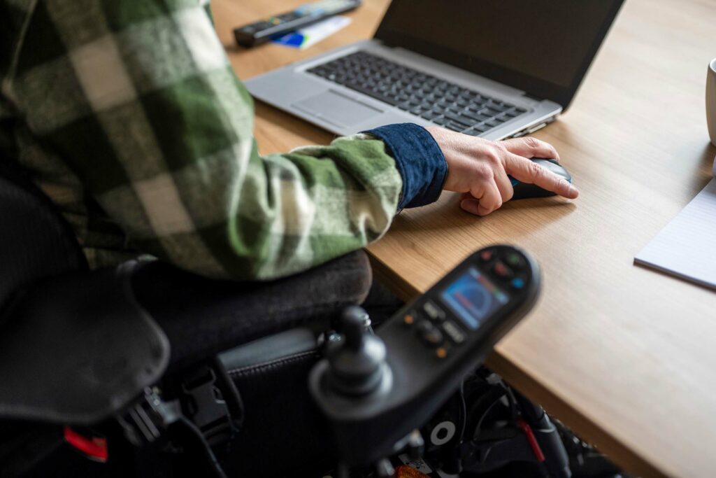 Barrierefreiheit auf Ihrer Website umsetzen: umprogrammieren oder neu aufsetzen? 1 Ein Mann im Rollstuhl arbeitet am Laptop mit der Maus